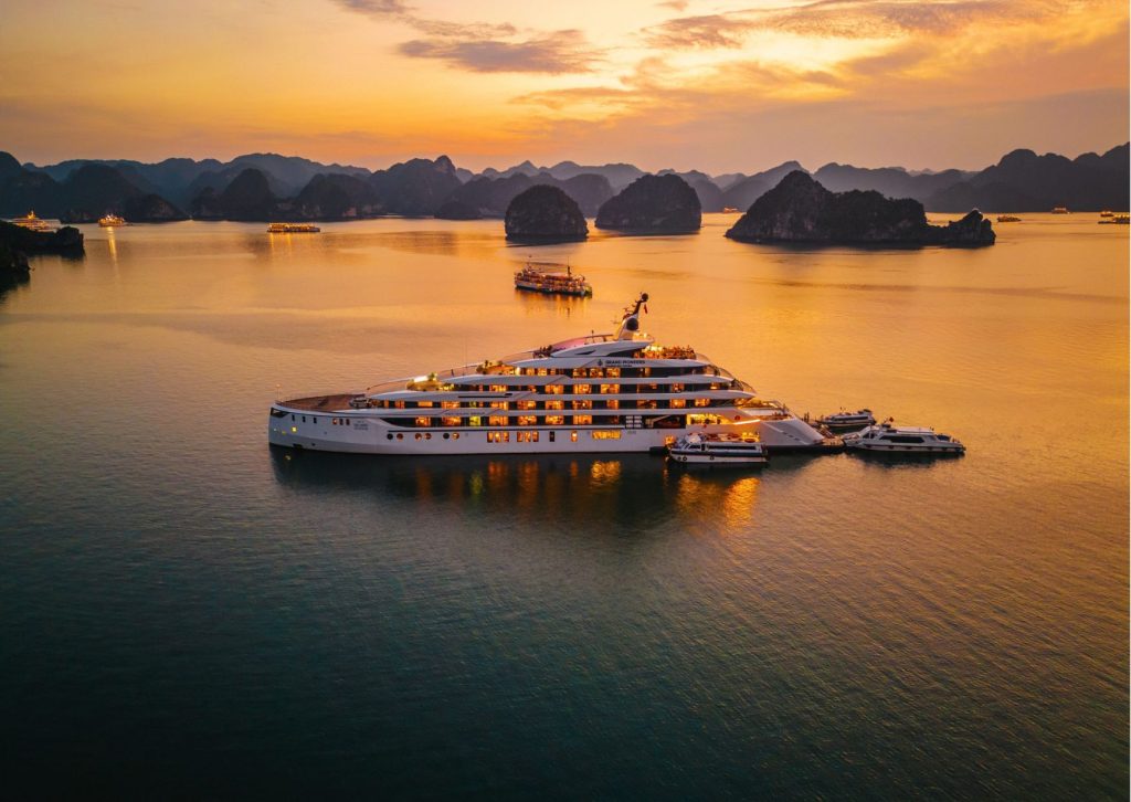 Luxury cruise ship at sunset among limestone karsts in Halong Bay.