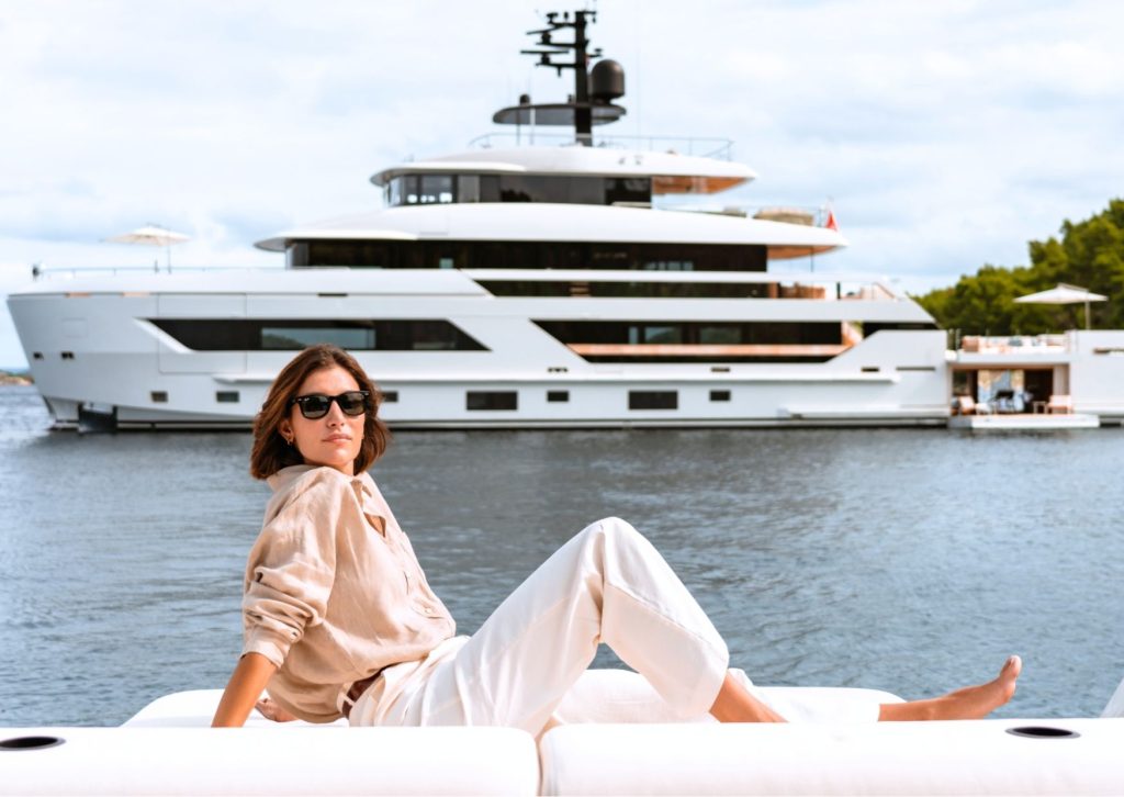 Woman relaxing on a boat with a massive white mega yacht behind